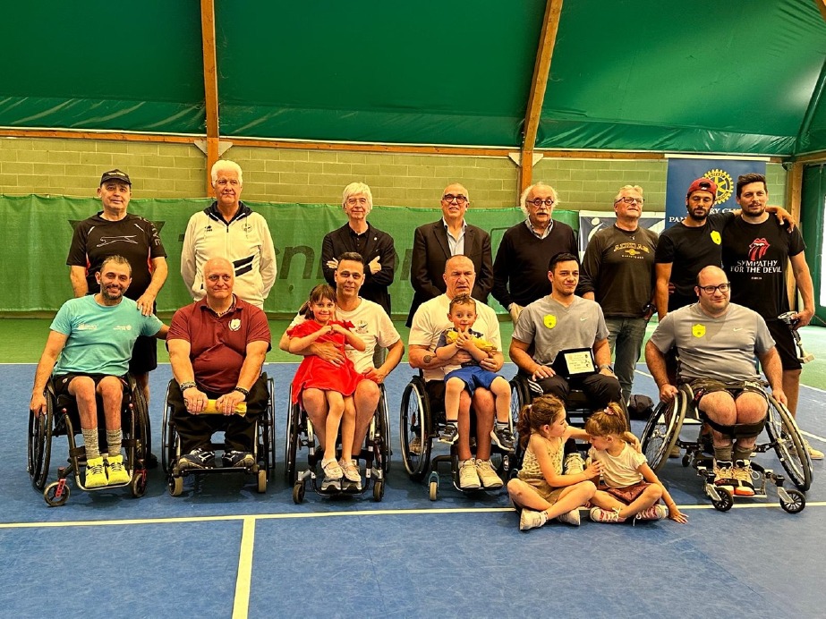 Wheelchair tennis players in competition on a court.